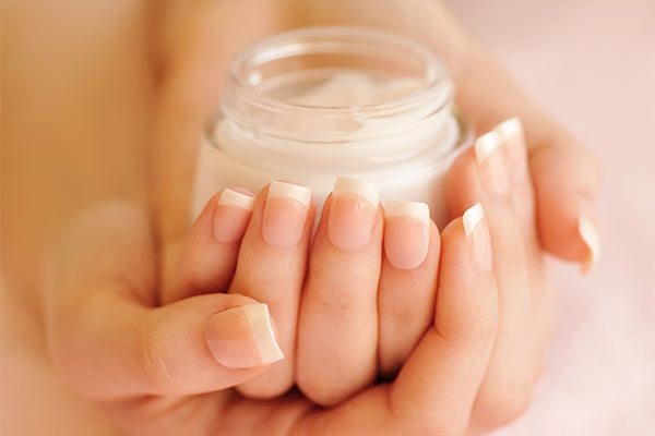 Image of a woman holding a jar of Daily Defense Rejuvenating Cream