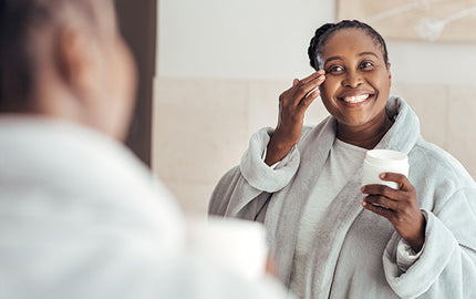 Image of Woman Using Exfoliating Cleanser in her Bathroom