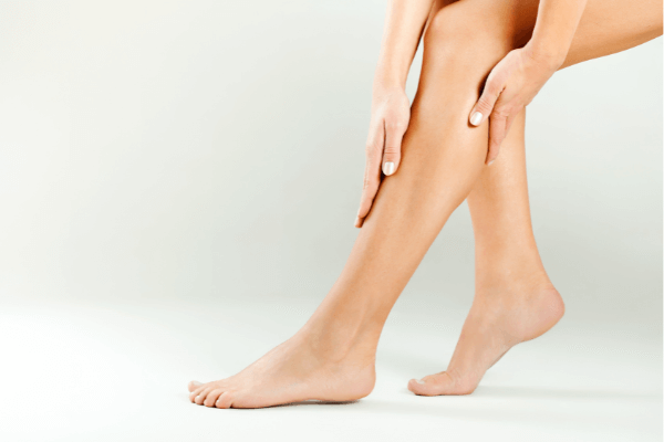 Image of someone applying massage oil on their legs and feet