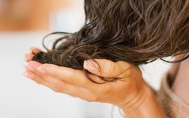 image of woman applying hemp seed hair oil for tired and damanged hair