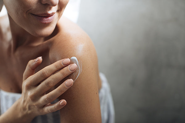 Image of a woman using the spray body lotion on her body