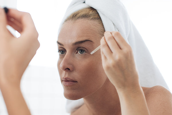 image of mature woman using facial oil suitable for skin prone to spider veins